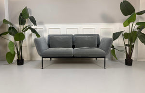 Gebrauchtes graues Brühl Roro Designer Stoff Sofa vor einer Wand, stilvoll und modern eingerichtet.