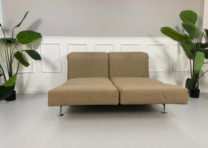 Gebrauchtes beiges Brühl Moule Designer Stoff Sofa vor einer Wand, stilvoll und modern eingerichtet.