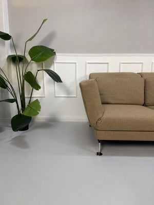 Gebrauchtes beiges Brühl Moule Designer Stoff Sofa vor einer Wand, stilvoll und modern eingerichtet.