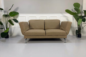 Gebrauchtes beiges Brühl Moule Designer Stoff Sofa vor einer Wand, stilvoll und modern eingerichtet.