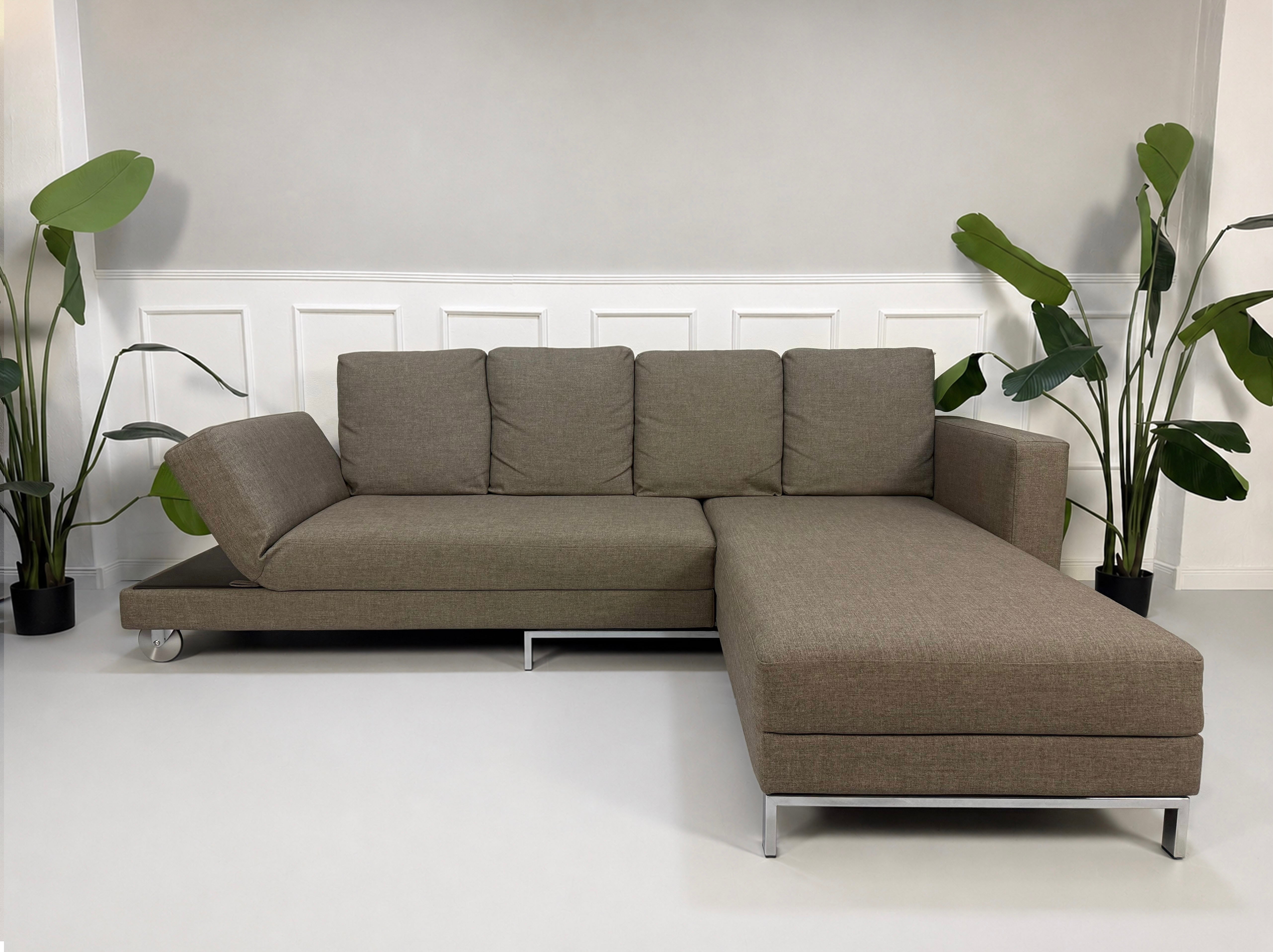 Gebrauchtes braunes Brühl Fourtwo Designer Stoff Sofa vor einer Wand, stilvoll und modern eingerichtet.