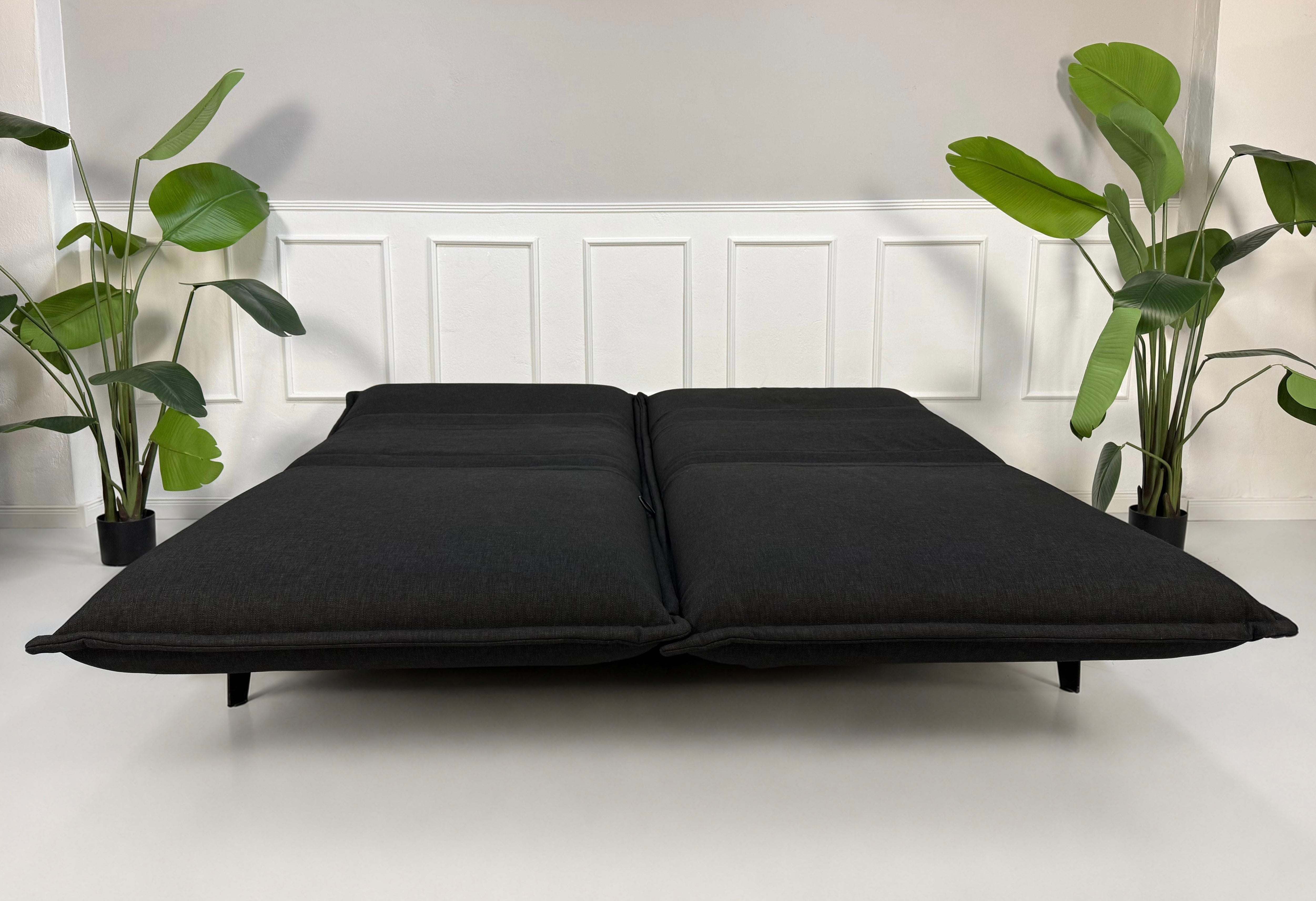 Gebrauchtes schwarzes Rolf Benz Nova Designer Stoff Sofa vor einer Wand, stilvoll und modern eingerichtet.