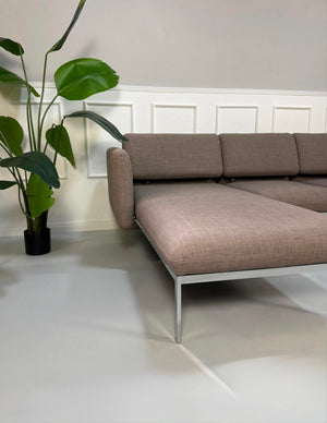 Gebrauchtes graues Brühl Roro Designer Stoff Ecksofa vor einer Wand, stilvoll und modern eingerichtet.