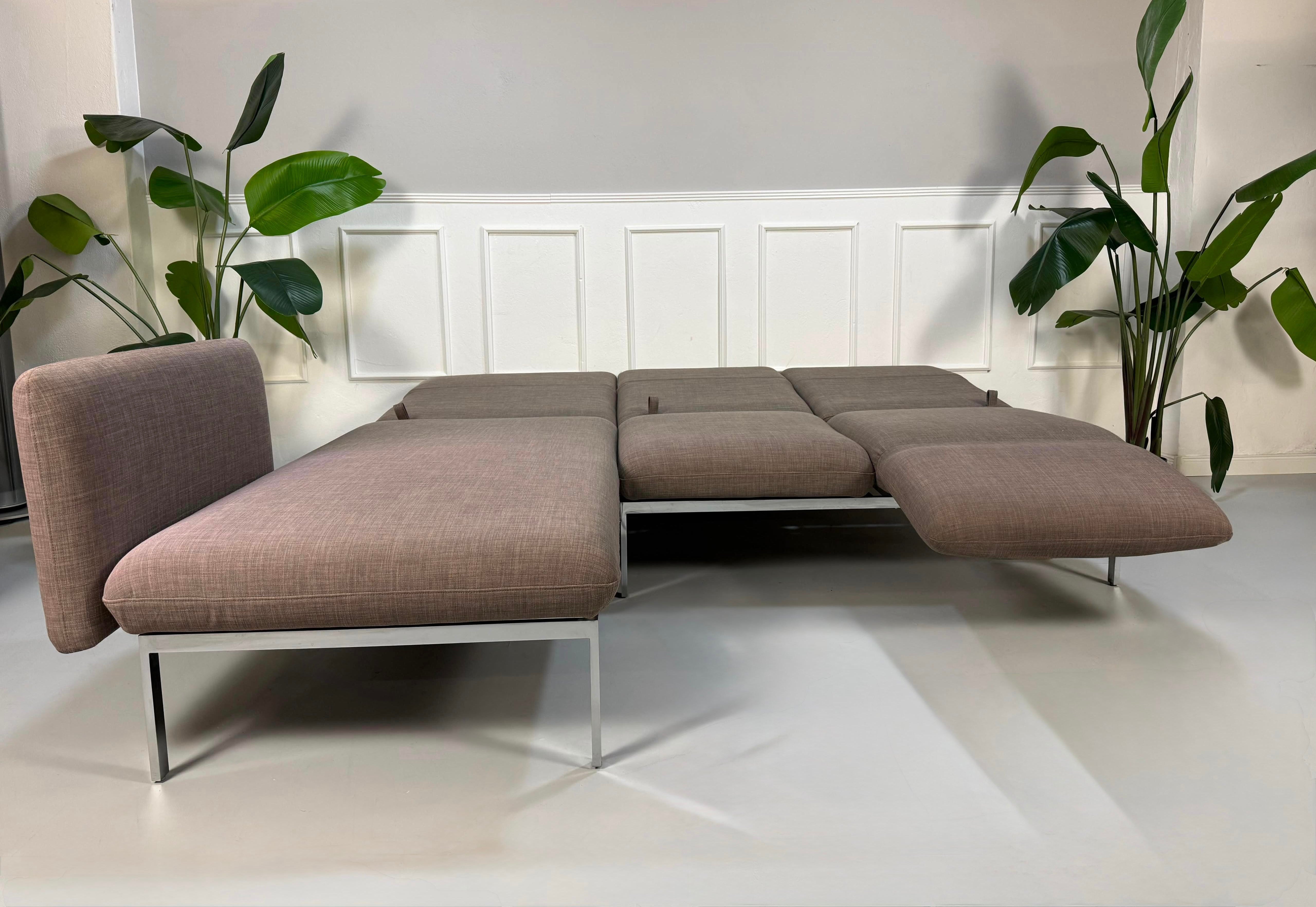 Gebrauchtes graues Brühl Roro Designer Stoff Ecksofa vor einer Wand, stilvoll und modern eingerichtet.