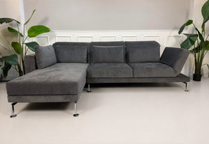 Ausstellungsstück Brühl Moule Designer Stoff Sofa in Grau vor einer Wand, stilvoll und modern eingerichtet.
