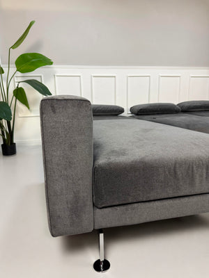 Ausstellungsstück Brühl Moule Designer Stoff Sofa in Grau vor einer Wand, stilvoll und modern eingerichtet.