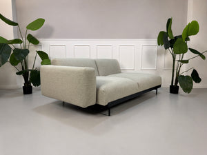 Gebrauchtes grau beiges Muuto In Situ Designer Stoff Sofa vor einer Wand, stilvoll und modern eingerichtet.