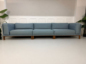 Gebrauchtes blaues Bolia Cosy Designer Stoff Sofa vor einer Wand, stilvoll und modern eingerichtet.