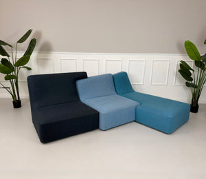 Gebrauchtes blaues Ligne Roset Confluences Designer Stoff Sofa vor einer Wand, stilvoll und modern eingerichtet.