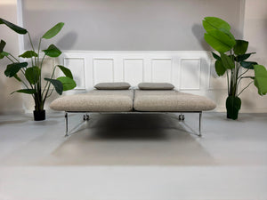 Fabrikverkauf Brühl Roro Designer Stoff Sofa vor einer Wand, stilvoll und modern eingerichtet.