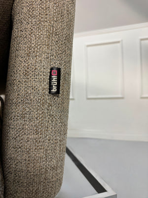Fabrikverkauf Brühl Roro Designer Stoff Sofa vor einer Wand, stilvoll und modern eingerichtet.
