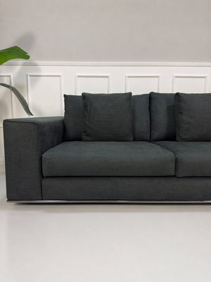 Gebrauchtes graues Minotti Hamilton Designer Stoff Sofa vor einer Wand, stilvoll und modern eingerichtet.