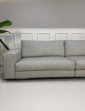 Ausstellungsstück graues Minotti Hamilton Designer Stoff Sofa vor einer Wand, stilvoll und modern eingerichtet.