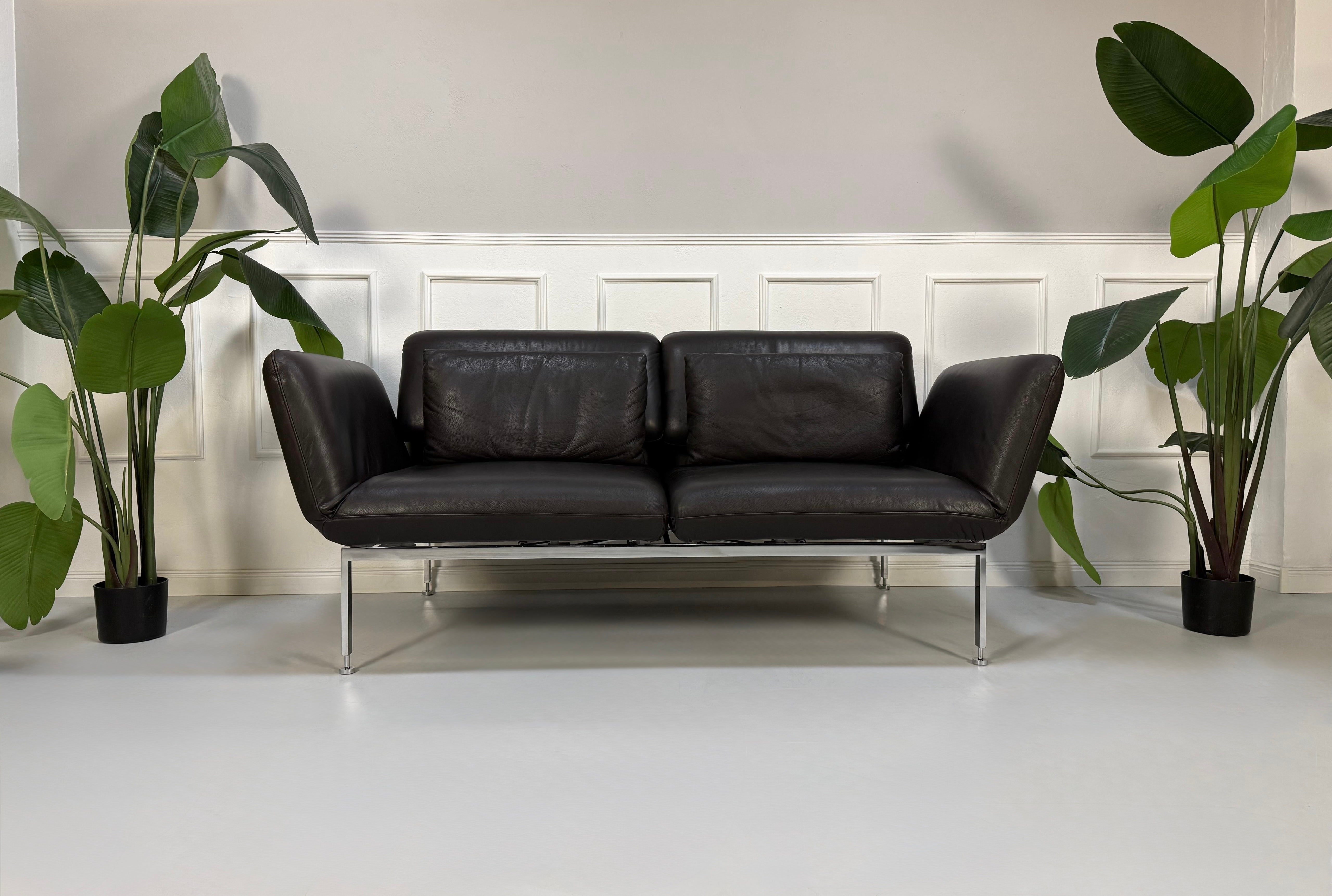Gebrauchtes schwarzes Brühl Roro Designer Leder Sofa vor einer Wand, stilvoll und modern eingerichtet.