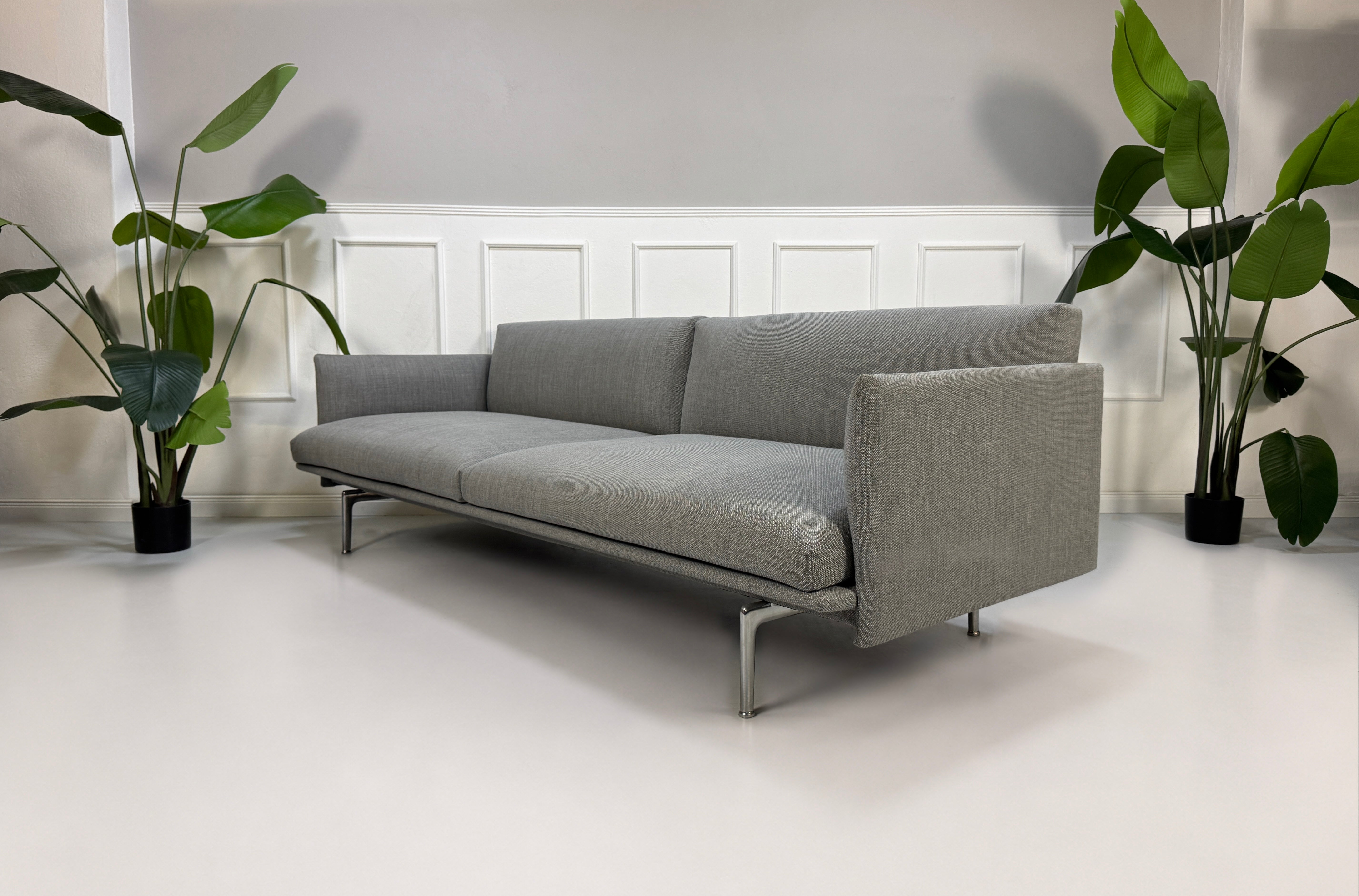 Gebrauchtes graues Muuto Outline Designer Stoff Sofa vor einer Wand, stilvoll und modern eingerichtet.