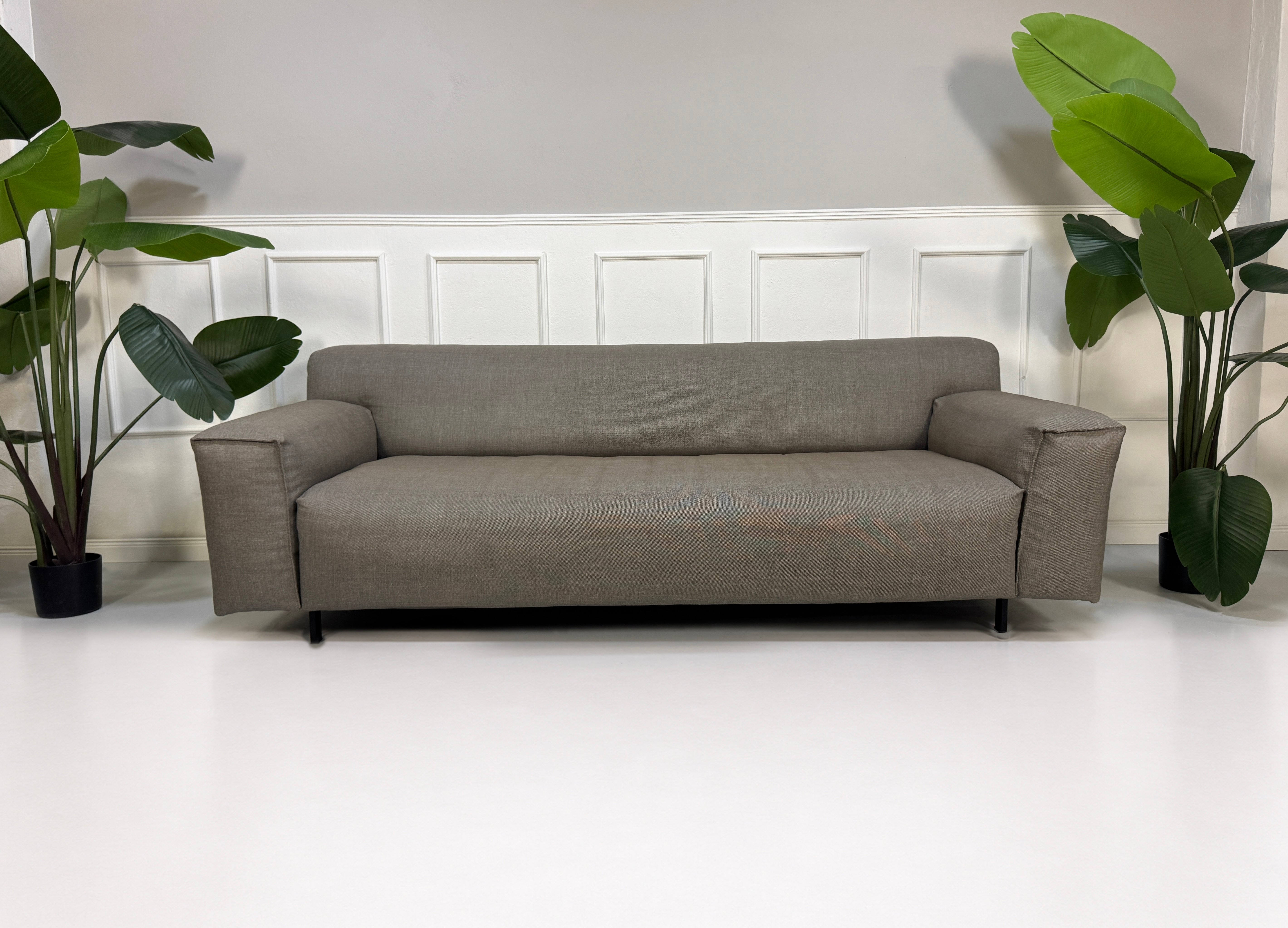 Gebrauchtes graues Rolf Benz Grata Designer Stoff Sofa mit Hocker vor einer Wand, stilvoll und modern eingerichtet.