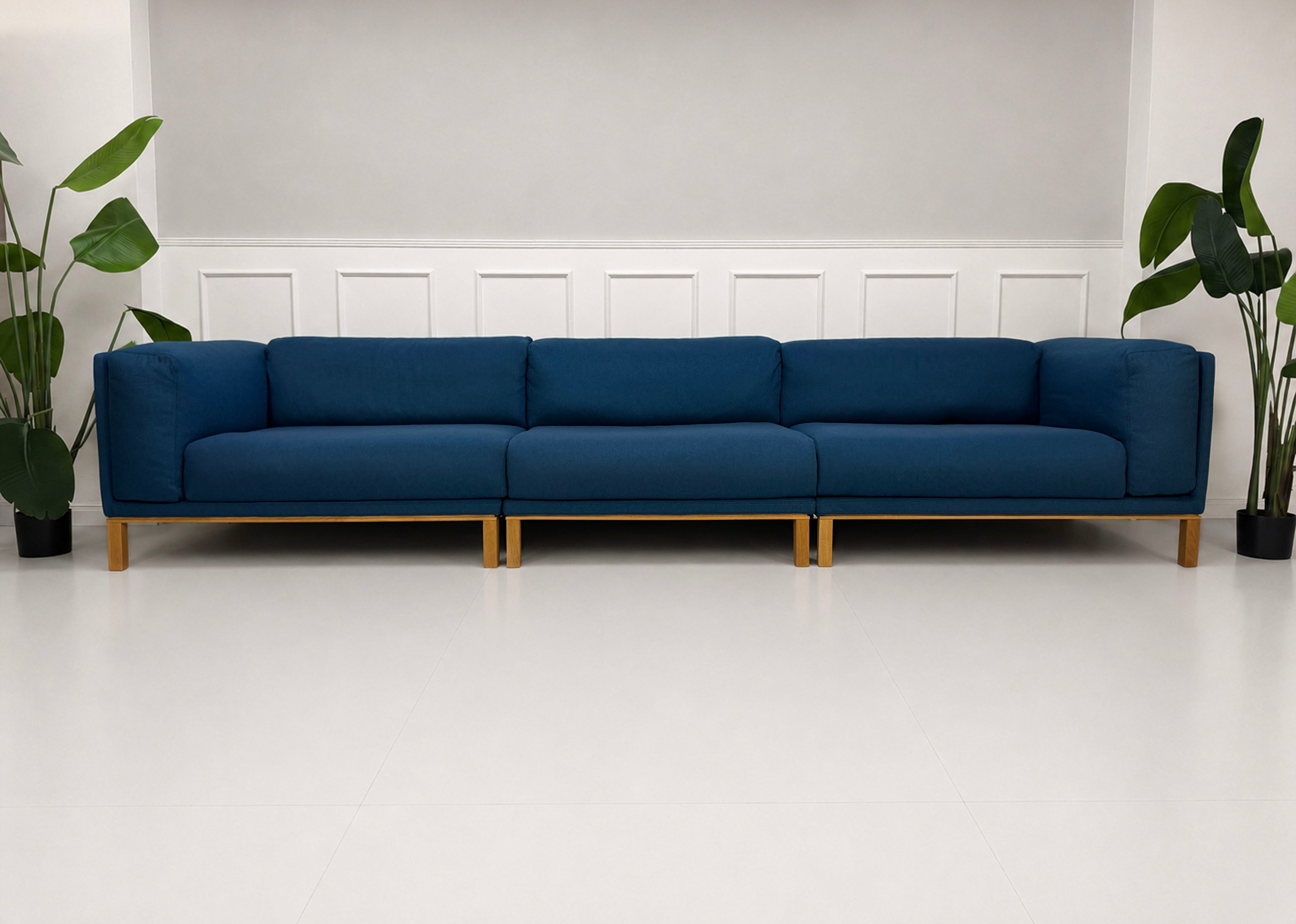 Gebrauchtes blaues Bolia Cosy Designer Stoff Sofa vor einer Wand, stilvoll und modern eingerichtet.