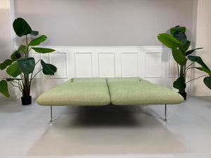 Fabrikverkauf grünes Brühl Roro Designer Stoff Sofa vor einer Wand, stilvoll und modern eingerichtet.