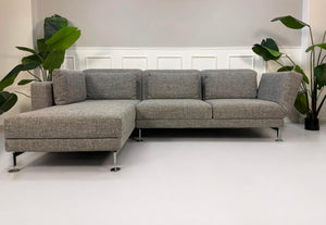 Gebrauchtes graues Brühl Designer Stoff Sofa vor einer Wand, stilvoll und modern eingerichtet.
