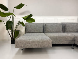 Gebrauchtes graues Brühl Moule Designer Stoff Sofa vor einer Wand, stilvoll und modern eingerichtet.