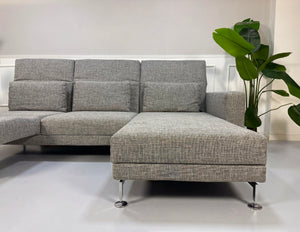 Gebrauchtes graues Brühl Moule Designer Stoff Sofa vor einer Wand, stilvoll und modern eingerichtet.