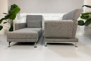 Gebrauchtes graues Brühl Designer Stoff Sofa vor einer Wand, stilvoll und modern eingerichtet.