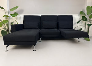 Gebrauchtes schwarzes Brühl Moule Designer Stoff Sofa vor einer Wand, stilvoll und modern eingerichtet.