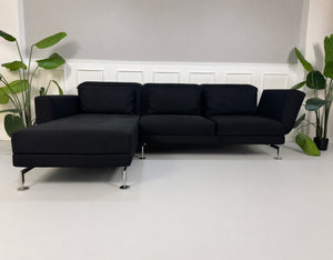 Gebrauchtes schwarzes Brühl Moule Designer Stoff Sofa vor einer Wand, stilvoll und modern eingerichtet.