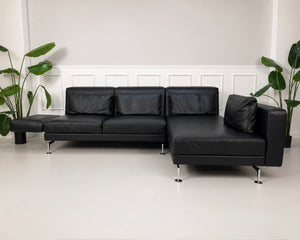 Gebrauchtes schwarzes Brühl Moule Designer Leder Sofa vor einer Wand, stilvoll und modern eingerichtet.