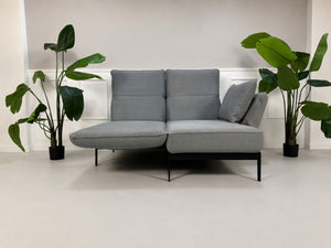 Gebrauchtes graues Rolf Benz Mera Designer Stoff Sofa vor einer Wand, stilvoll und modern eingerichtet.