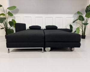 Gebrauchtes schwarzes Brühl Fourtwo Designer Stoff Sofa vor einer Wand, stilvoll und modern eingerichtet.