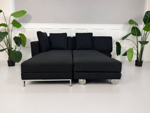 Gebrauchtes schwarzes Brühl Fourtwo Designer Stoff Sofa vor einer Wand, stilvoll und modern eingerichtet.
