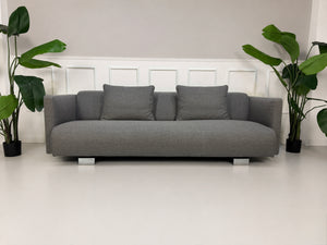 Gebrauchtes graues Rolf Benz 6300 Designer Stoff Sofa vor einer Wand, stilvoll und modern eingerichtet.