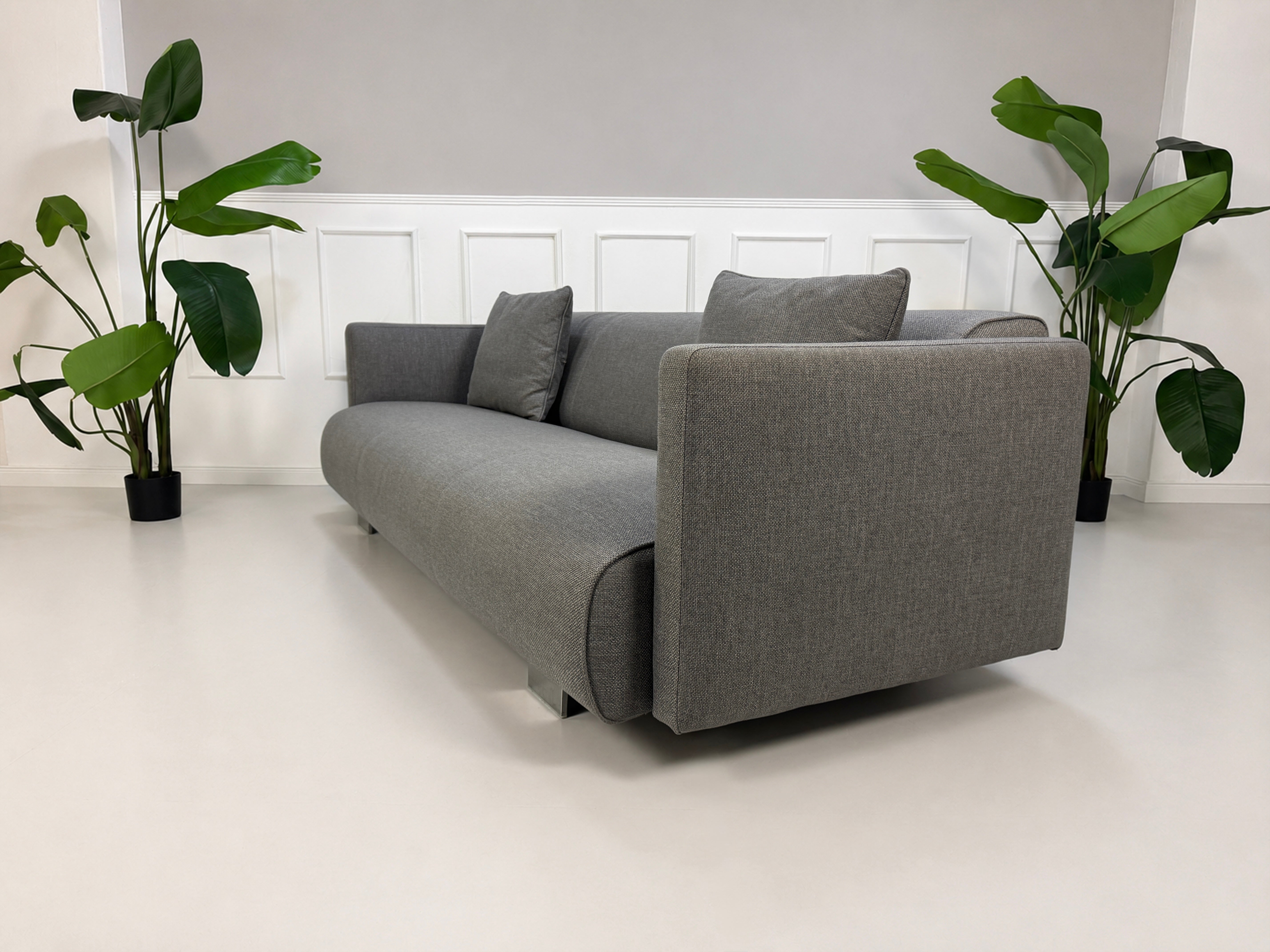 Gebrauchtes graues Rolf Benz 6300 Designer Stoff Sofa vor einer Wand, stilvoll und modern eingerichtet.