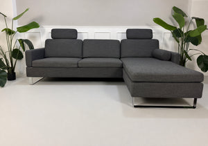 Gebrauchtes graues Brühl Alba Designer Stoff Sofa vor einer Wand, stilvoll und modern eingerichtet.