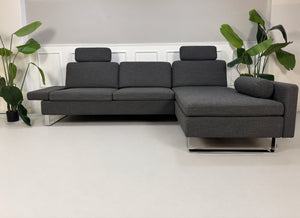 Gebrauchtes graues Brühl Alba Designer Stoff Sofa vor einer Wand, stilvoll und modern eingerichtet.