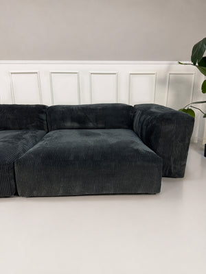 Gebrauchtes graues Vetsak Designer Stoff Sofa vor einer Wand, stilvoll und modern eingerichtet.
