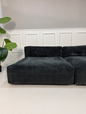 Gebrauchtes graues Vetsak Designer Stoff Sofa vor einer Wand, stilvoll und modern eingerichtet.