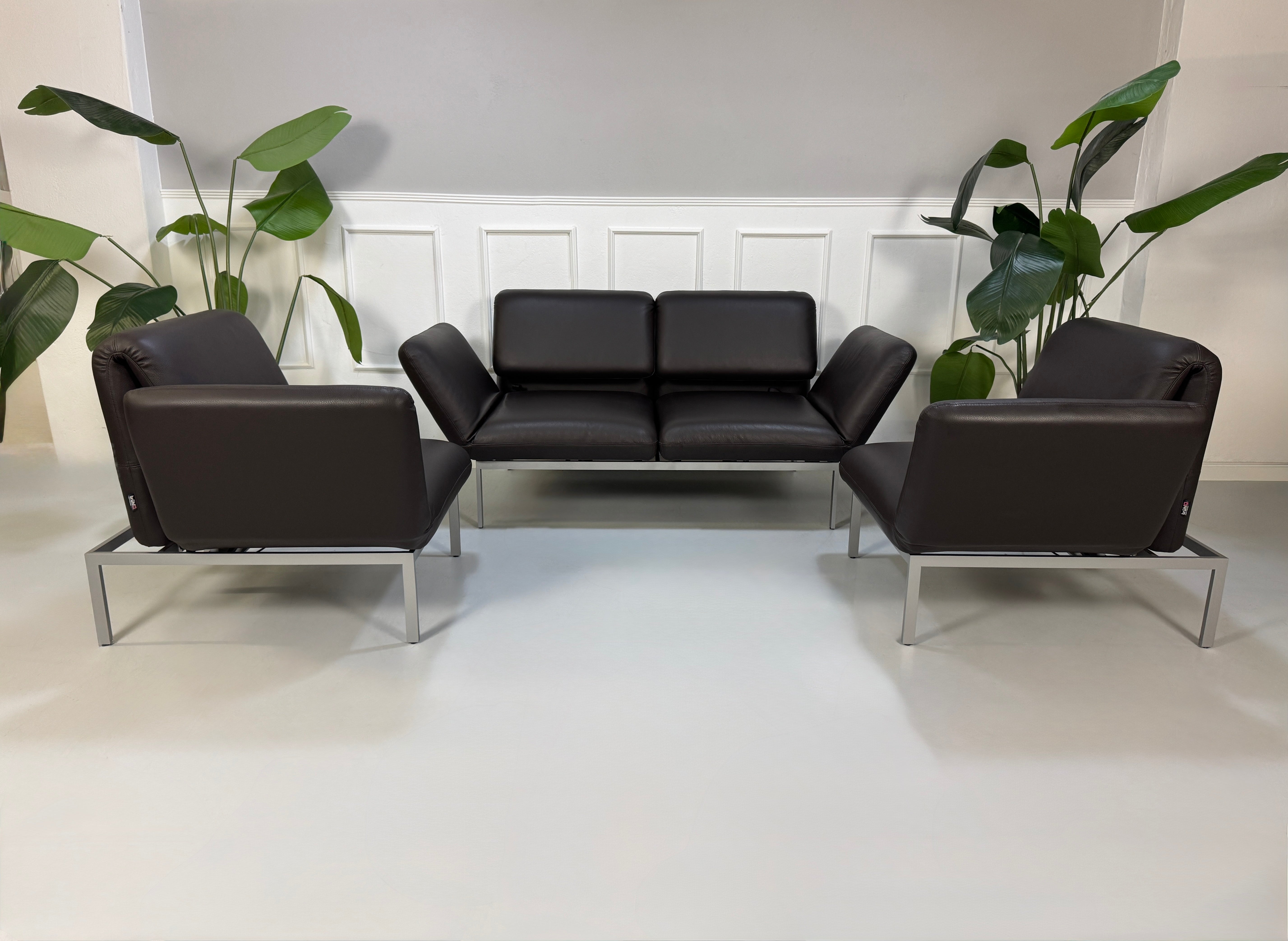 Gebrauchte braune Brühl Roro Designer Leder Sofas vor einer Wand, stilvoll und modern eingerichtet.