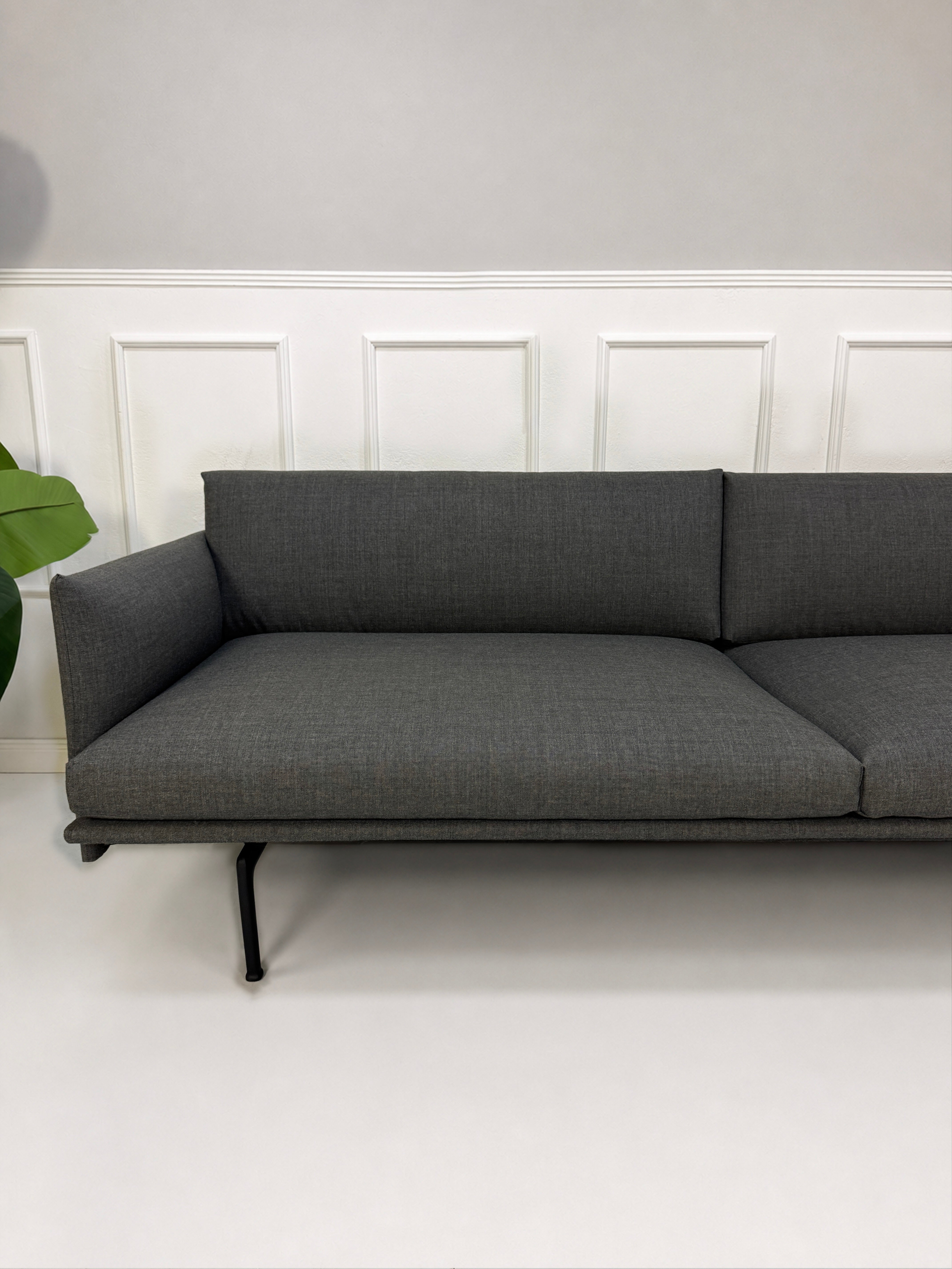 Gebrauchtes graues Muuto Outline Designer Stoff Sofa vor einer Wand, stilvoll und modern eingerichtet.