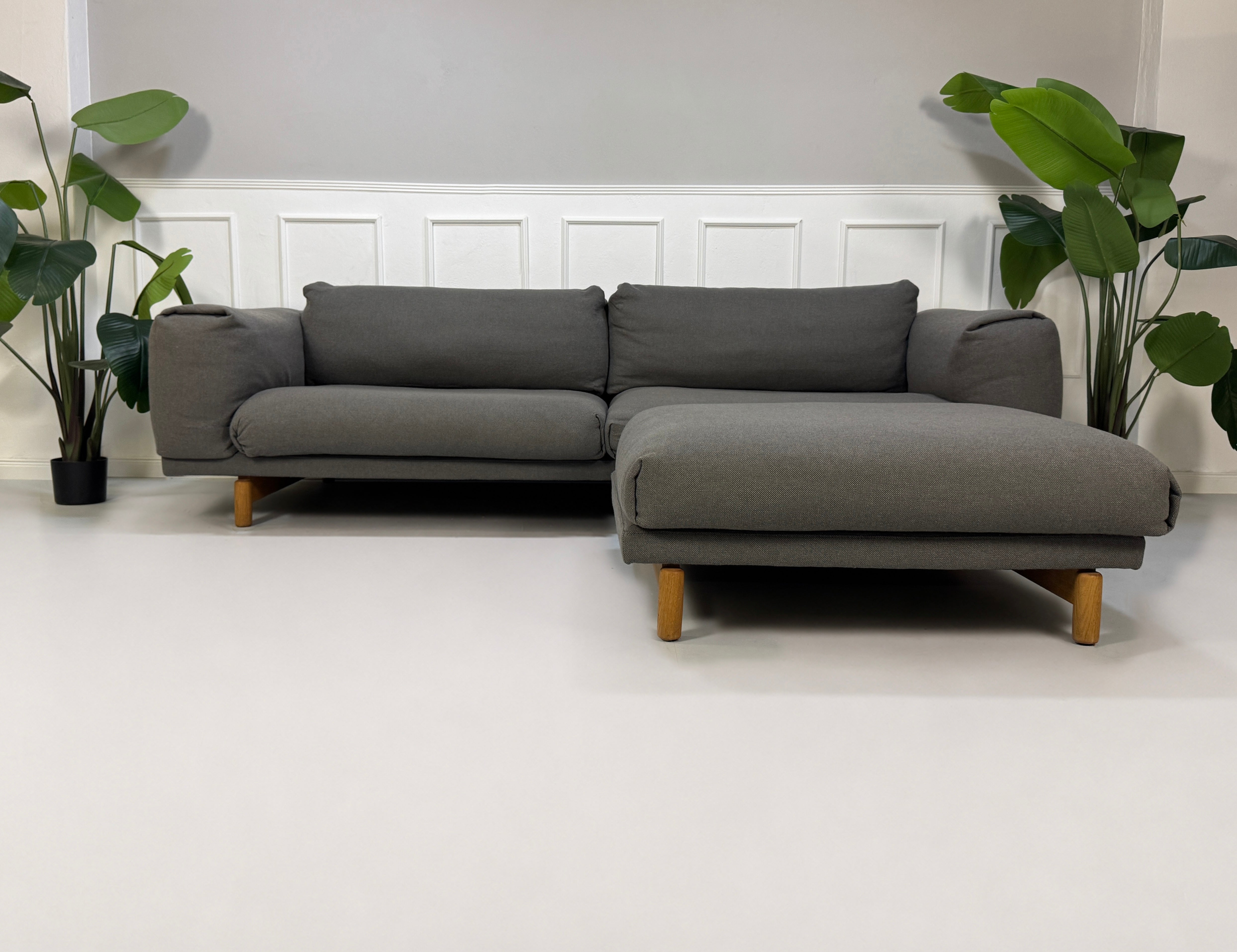 Gebrauchtes graues Muuto Rest Designer Stoff Sofa mit Hocker vor einer Wand, stilvoll und modern eingerichtet.