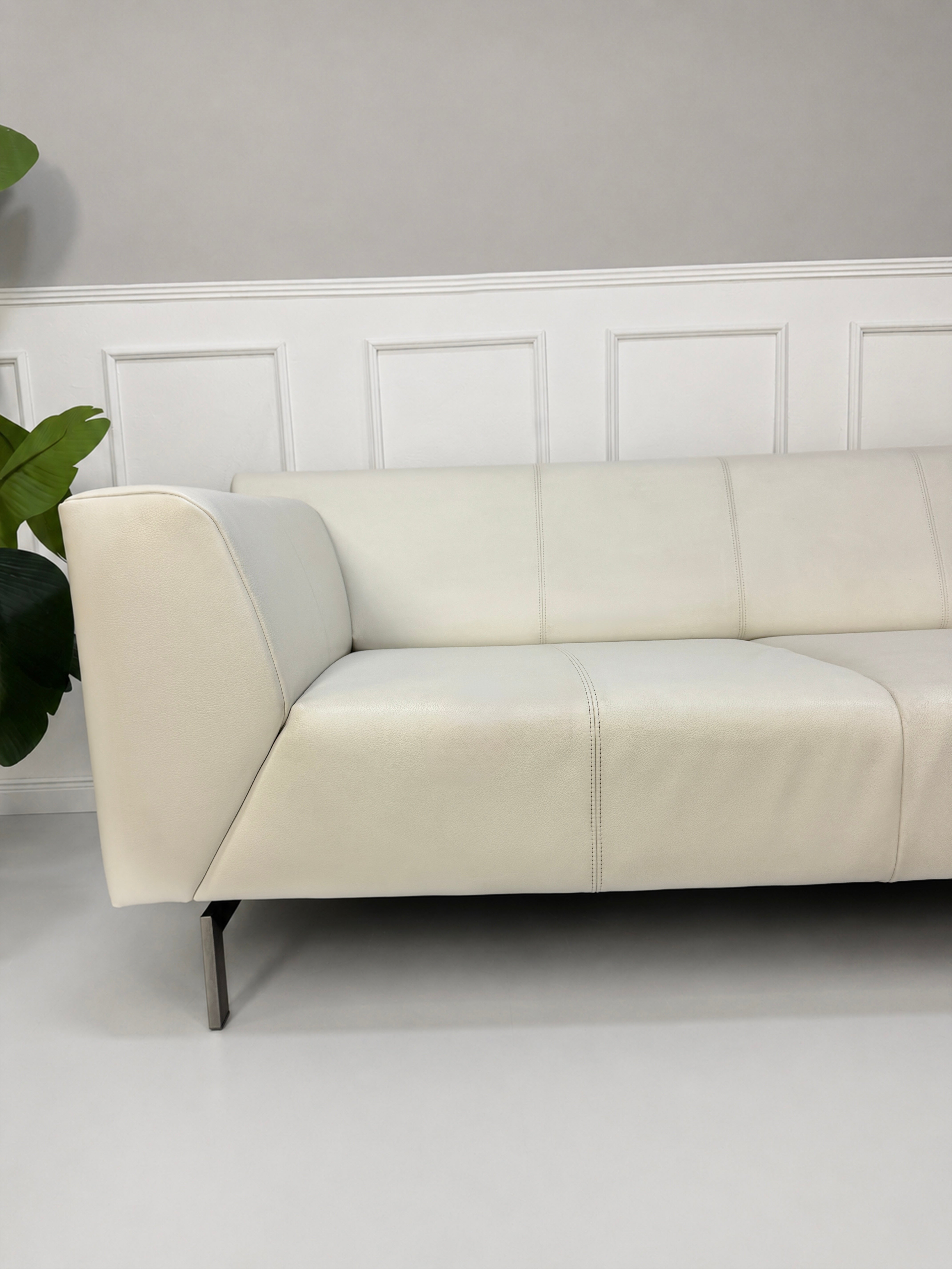 Gebrauchtes weißes Rolf Benz Linea 318 Designer Leder Sofa vor einer Wand, stilvoll und modern eingerichtet.