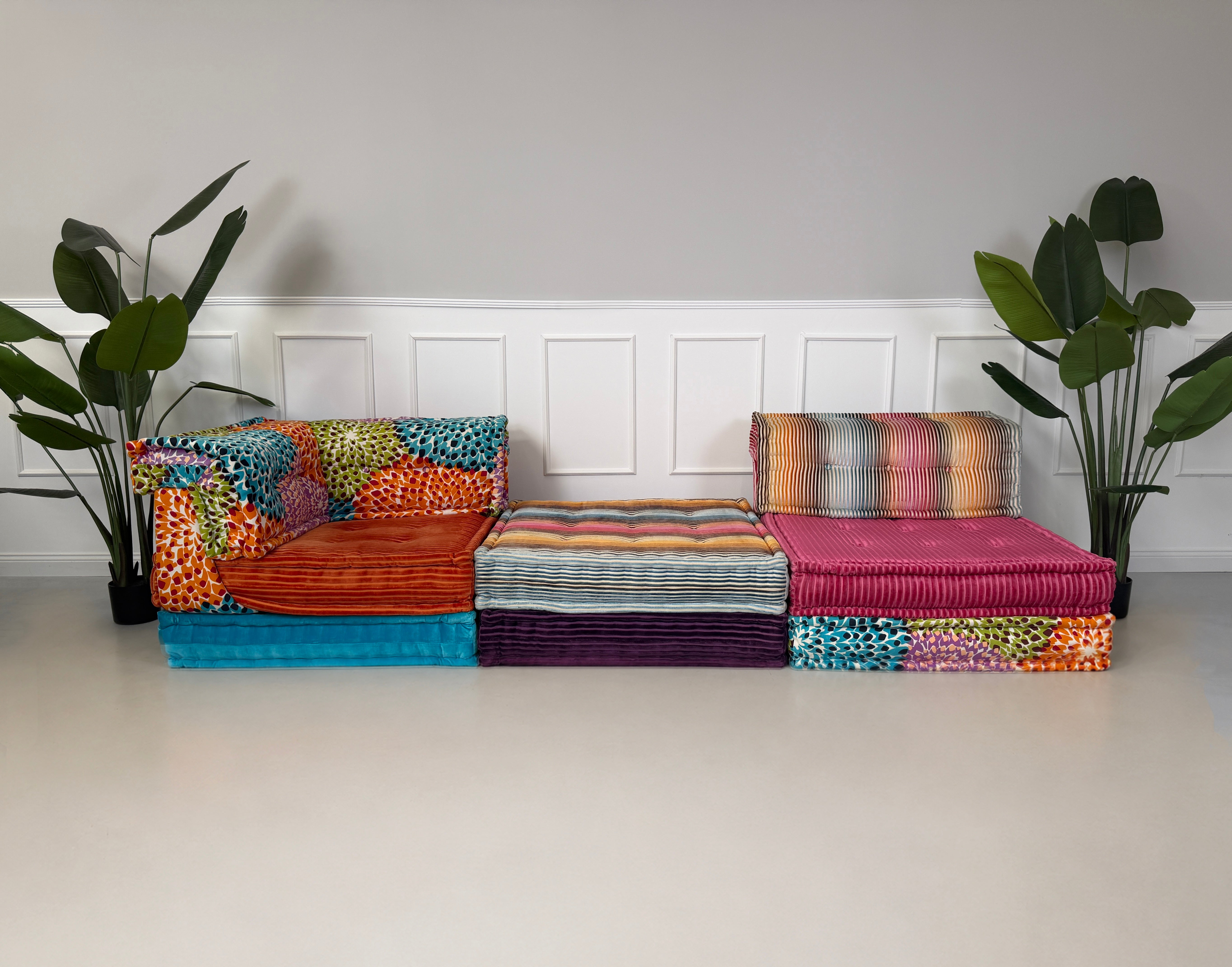 Gebrauchtes buntes Roche Bobois Mah Jong Modulsofa in Missoni-Stoffen, frontal als Sitzreihe vor einer weißen Wand aufgestellt.