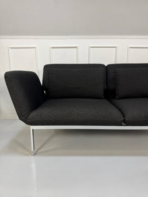 Gebrauchtes graues Brühl Roro Designer Stoff Sofa vor einer Wand, stilvoll und modern eingerichtet.