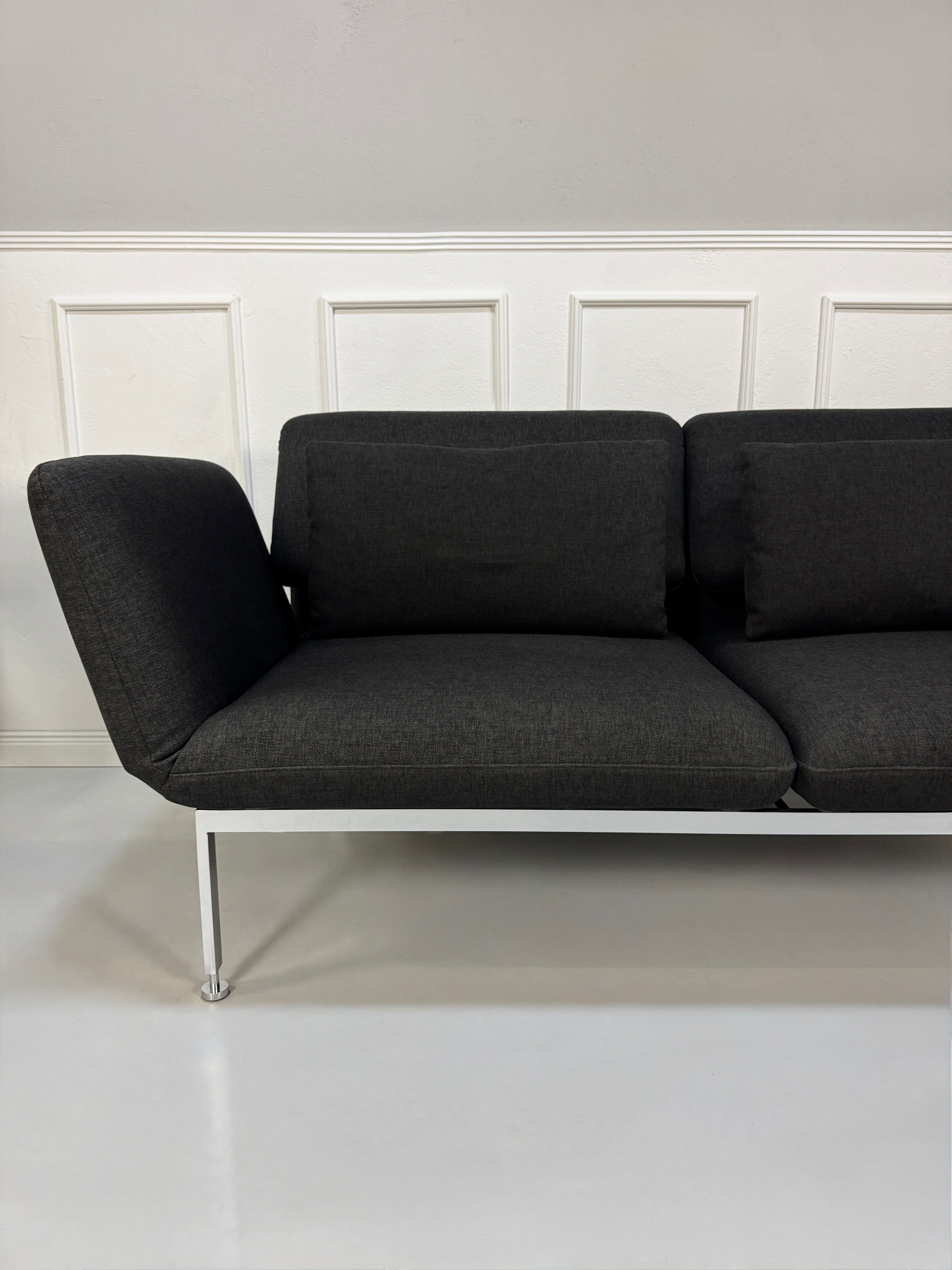Gebrauchtes graues Brühl Roro Designer Stoff Sofa vor einer Wand, stilvoll und modern eingerichtet.