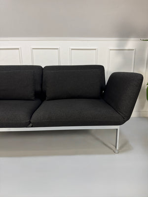 Gebrauchtes graues Brühl Roro Designer Stoff Sofa vor einer Wand, stilvoll und modern eingerichtet.