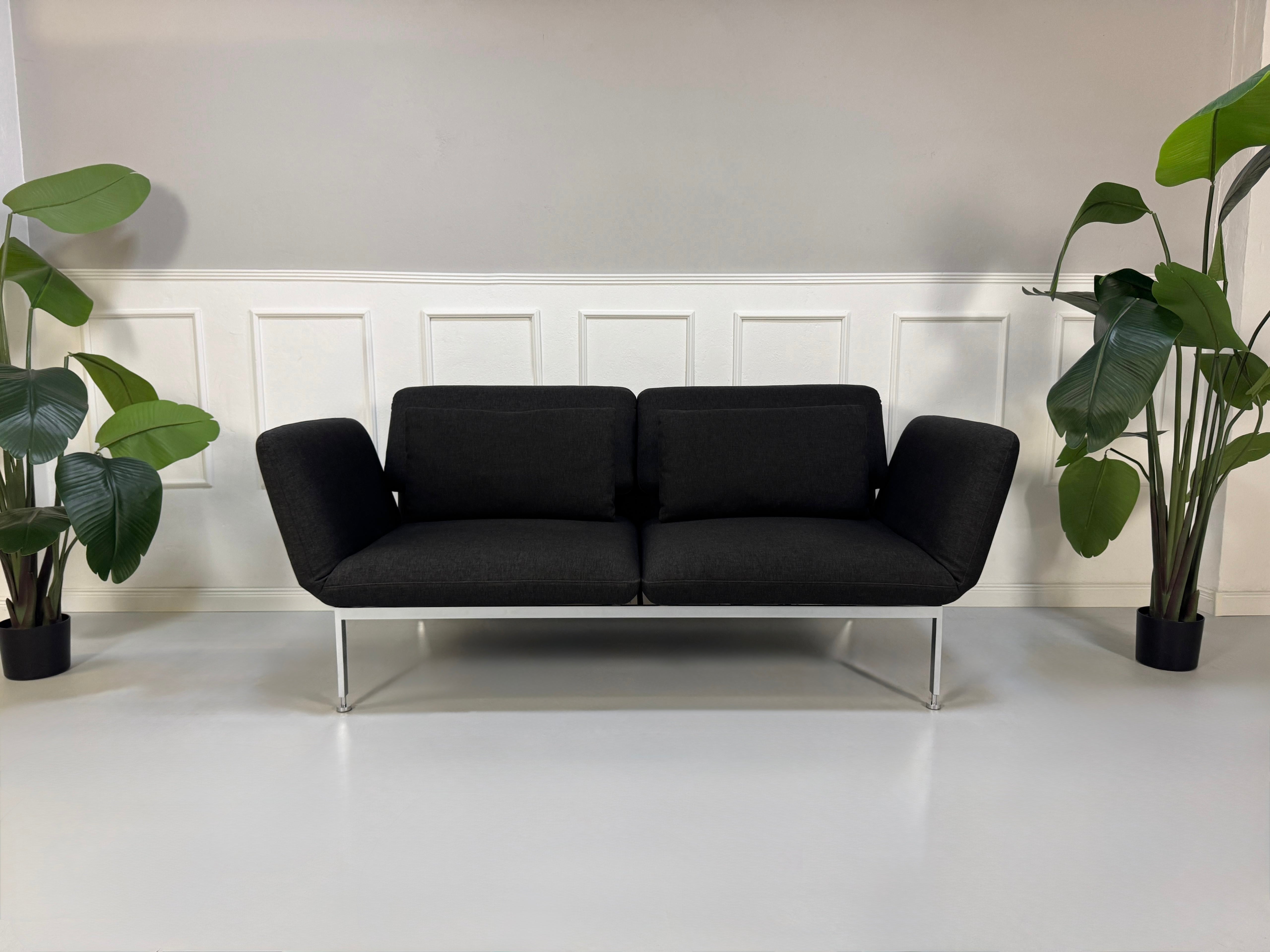 Gebrauchtes graues Brühl Roro Designer Stoff Sofa vor einer Wand, stilvoll und modern eingerichtet.