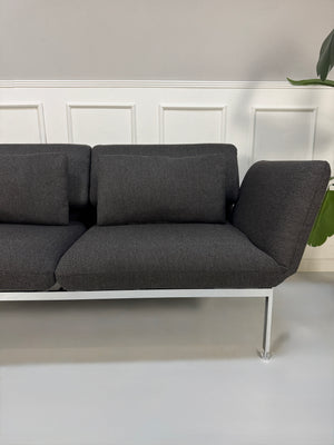 Gebrauchtes graues Brühl Roro Designer Stoff Sofa vor einer Wand, stilvoll und modern eingerichtet.