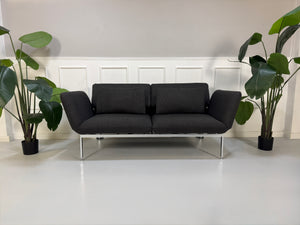 Gebrauchtes graues Brühl Roro Designer Stoff Sofa vor einer Wand, stilvoll und modern eingerichtet.