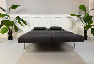 Gebrauchtes graues Brühl Roro Soft Designer Stoff Sofa vor einer Wand, stilvoll und modern eingerichtet.